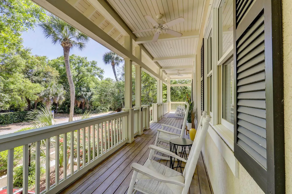 A tranquil porch scene with comfortable chairs, potted plants, and a ceiling fan, inviting guests to relax before or after their island adventures. The porch setting hints at the home’s welcoming entry and flow between interior and exterior spaces.