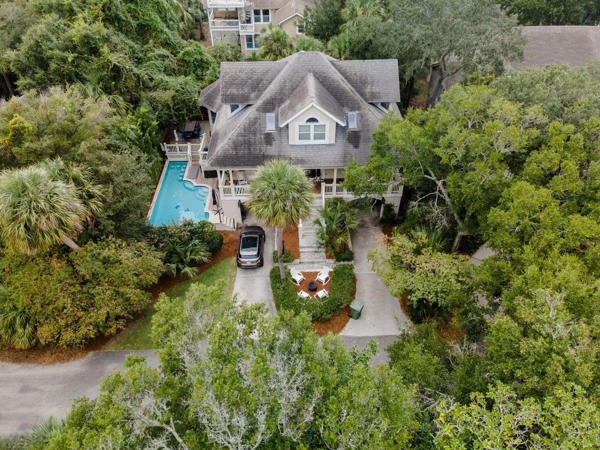 A wide view of the large backyard showcases the sparkling swimming pool surrounded by lush greenery, ample outdoor seating, and the exterior of the house. The scene exudes a sense of privacy, relaxation, and resort-like indulgence, making it ideal for family gatherings and leisure.