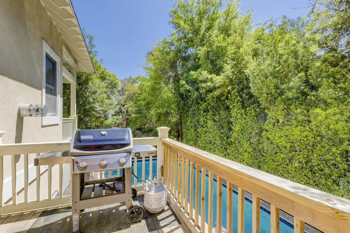 A grill and deck area overlooking lush greenery, perfect for outdoor gatherings and poolside barbecues. The scene suggests casual outdoor living and seamless transitions between relaxing, dining, and entertaining.