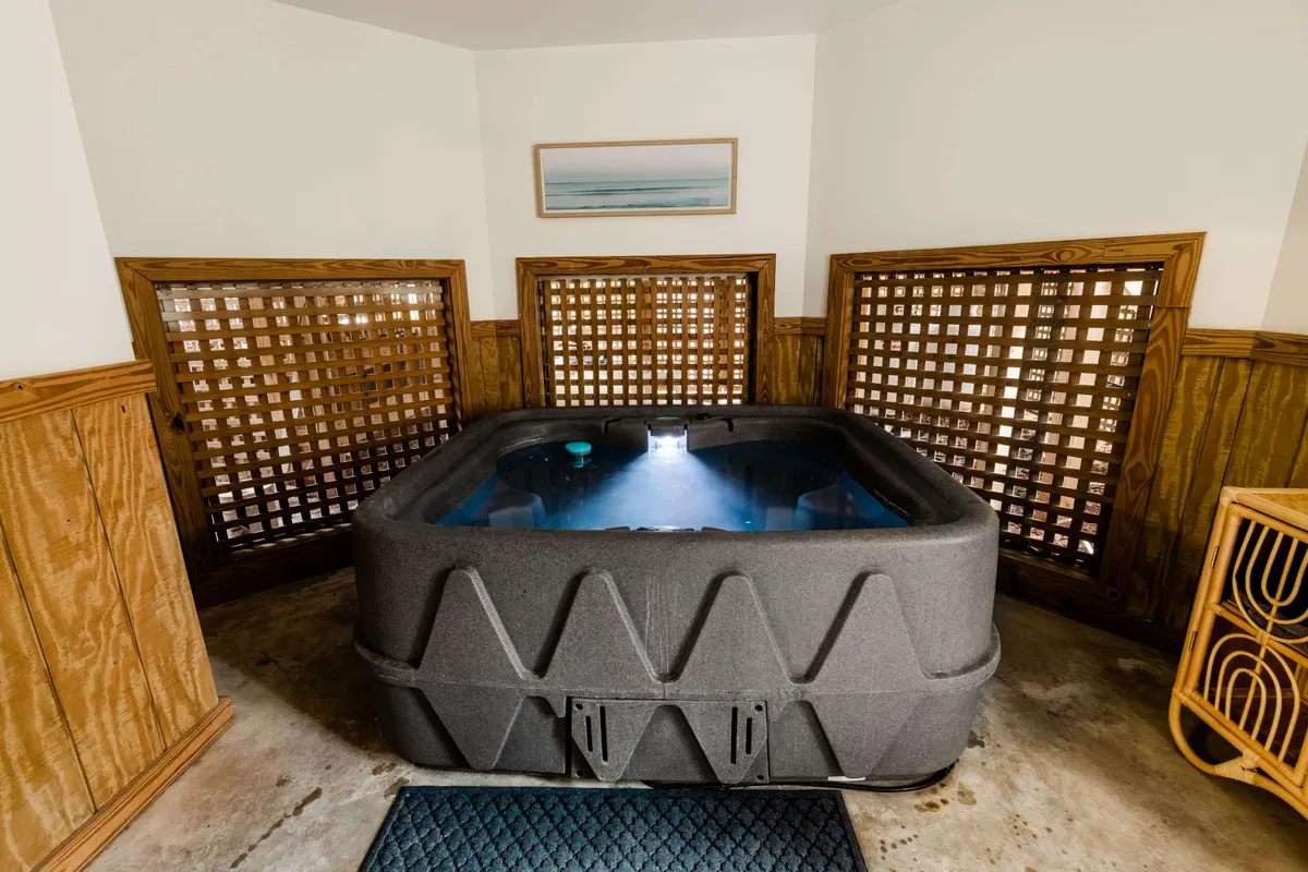 An inviting hot tub area indoors, framed by wooden lattice screens and tasteful decor. The space is designed for intimate relaxation, socializing, or a soothing soak after a day of fun outdoors.