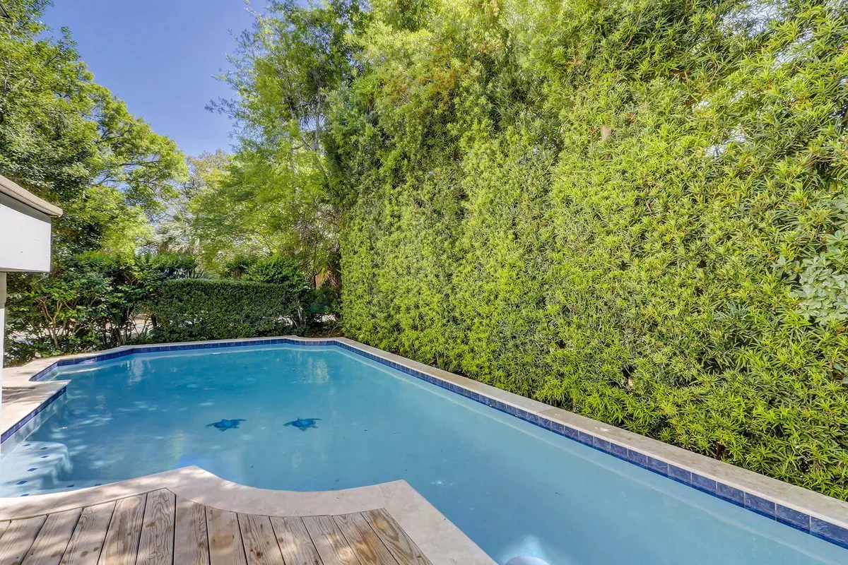 A closer exterior shot of the swimming pool bordered by lush landscaping and a spacious deck. The tranquil setting highlights the refreshing water and inviting atmosphere, ideal for sunbathing, socializing, or relaxing by the pool day or night.